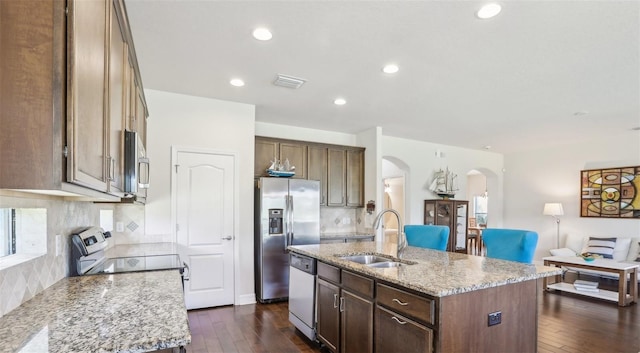 kitchen featuring arched walkways, light stone counters, a sink, visible vents, and appliances with stainless steel finishes