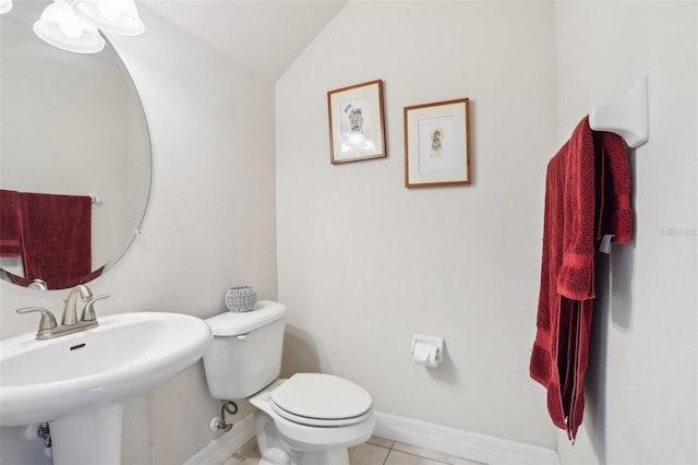 half bathroom featuring baseboards, toilet, tile patterned flooring, vaulted ceiling, and a sink