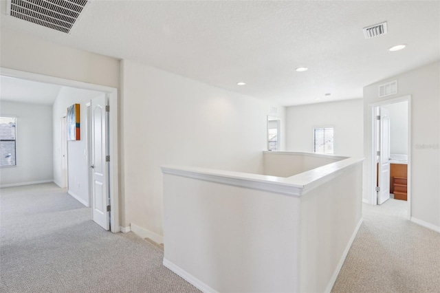 hallway featuring a healthy amount of sunlight, visible vents, and an upstairs landing