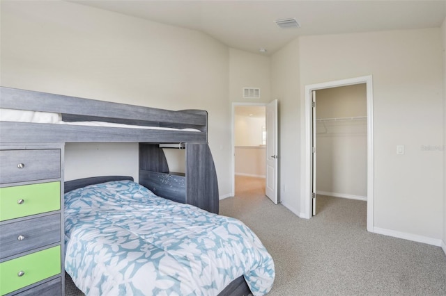 bedroom featuring visible vents, baseboards, vaulted ceiling, a spacious closet, and carpet