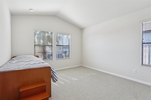 carpeted bedroom with lofted ceiling and baseboards