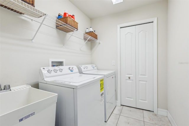 clothes washing area featuring laundry area, light tile patterned floors, baseboards, washing machine and clothes dryer, and a sink