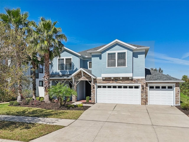 view of front of home with driveway, stone siding, a garage, and stucco siding