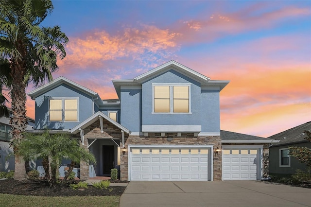 view of front of home with a garage, stone siding, concrete driveway, and stucco siding