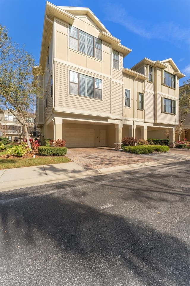 view of front facade featuring decorative driveway, an attached garage, and stucco siding