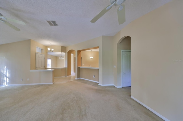 unfurnished living room featuring a textured ceiling, arched walkways, light colored carpet, ceiling fan with notable chandelier, and visible vents