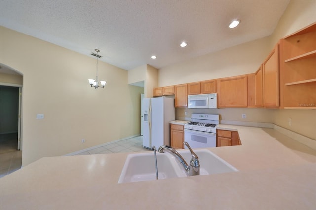 kitchen featuring arched walkways, decorative light fixtures, light countertops, a sink, and white appliances