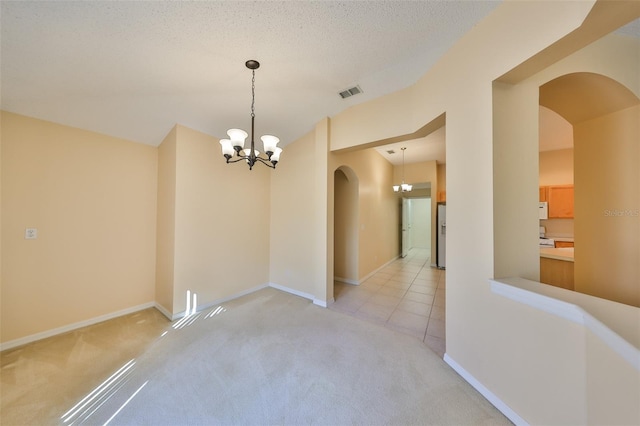 unfurnished dining area featuring light carpet, an inviting chandelier, visible vents, and arched walkways