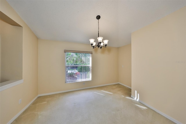 spare room featuring carpet flooring, a textured ceiling, baseboards, and an inviting chandelier