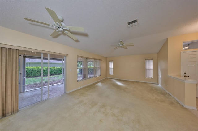 empty room featuring lofted ceiling, a textured ceiling, light colored carpet, visible vents, and baseboards