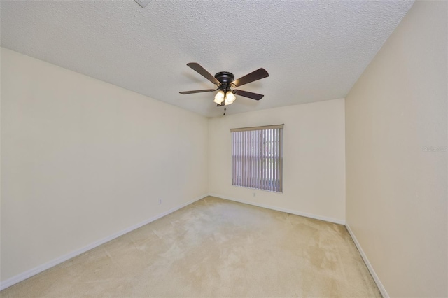 empty room with a ceiling fan, baseboards, a textured ceiling, and light colored carpet