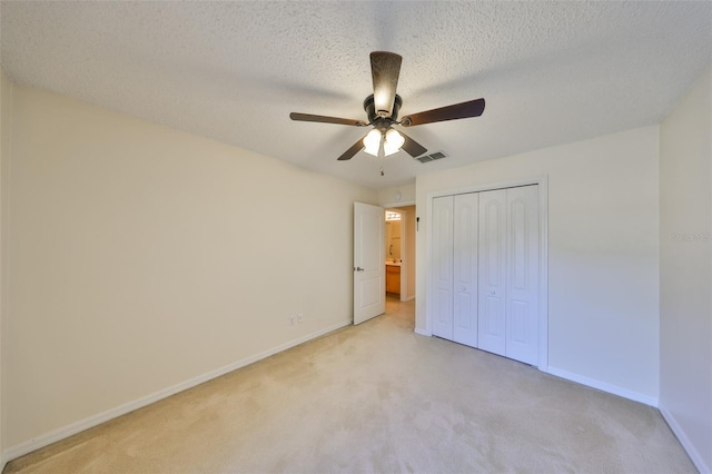 unfurnished bedroom with a textured ceiling, baseboards, a closet, and light colored carpet