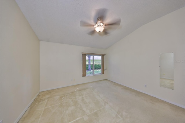 empty room featuring lofted ceiling, baseboards, a ceiling fan, and light colored carpet