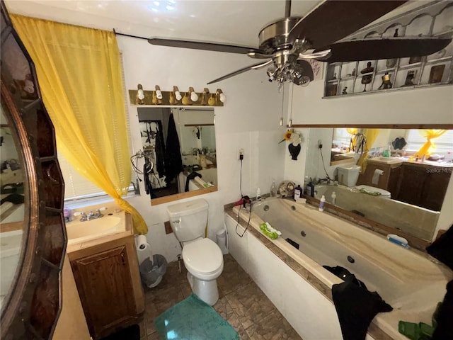 bathroom with vanity, a tub with jets, a ceiling fan, tile patterned floors, and toilet