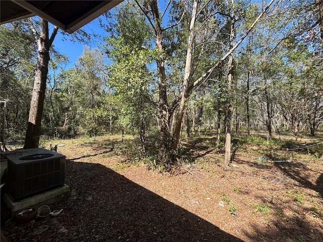 view of yard with central air condition unit and a forest view