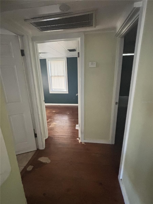 corridor with baseboards, visible vents, wood finished floors, and ornamental molding