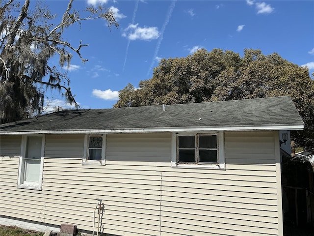 view of side of home with roof with shingles