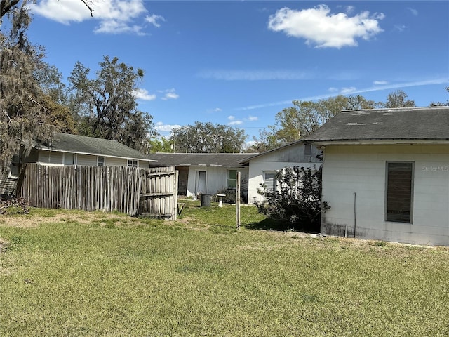 rear view of house featuring a lawn and fence