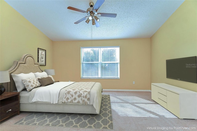 bedroom featuring light carpet, a textured ceiling, a ceiling fan, and baseboards