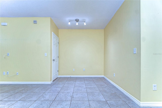 empty room with light tile patterned floors and baseboards