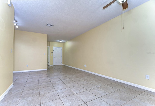 empty room featuring light tile patterned floors, a textured ceiling, visible vents, baseboards, and a ceiling fan