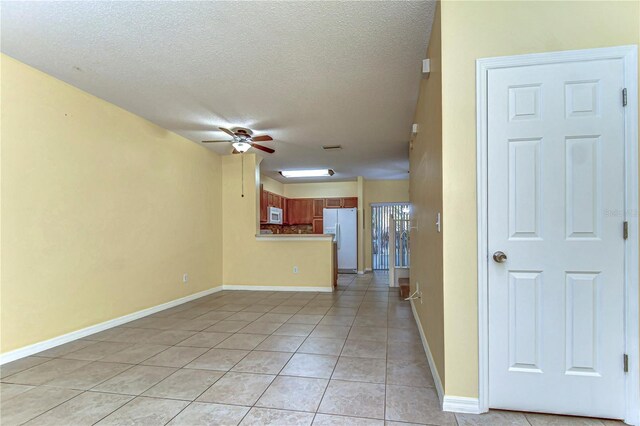 spare room featuring light tile patterned floors, ceiling fan, baseboards, and a textured ceiling