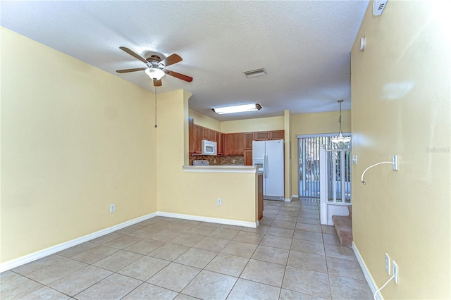 kitchen featuring white appliances, visible vents, decorative backsplash, a peninsula, and ceiling fan with notable chandelier