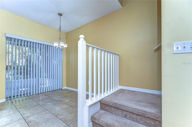 staircase featuring a notable chandelier, baseboards, and tile patterned floors