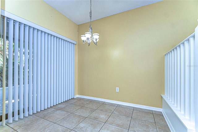 tiled empty room featuring baseboards and a chandelier