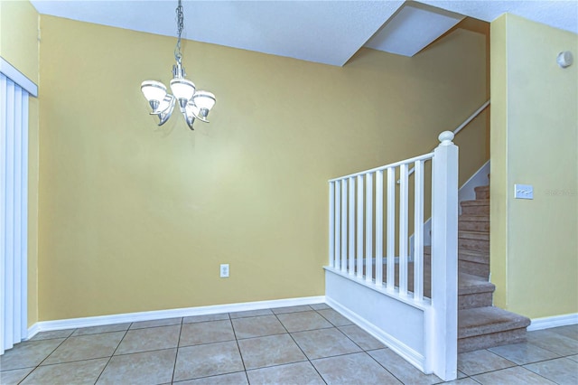 tiled spare room with an inviting chandelier, stairs, and baseboards