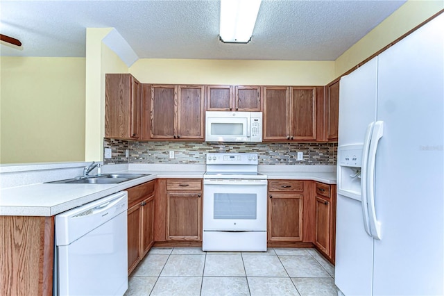 kitchen featuring light tile patterned floors, light countertops, a sink, white appliances, and a peninsula