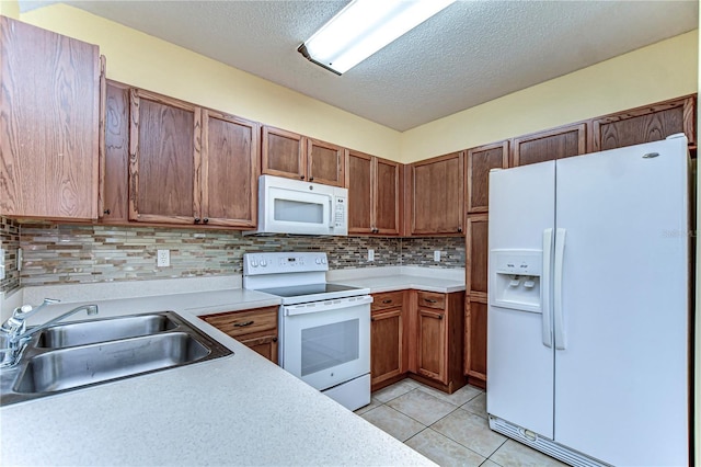 kitchen featuring white appliances, decorative backsplash, light countertops, a sink, and light tile patterned flooring