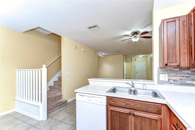 kitchen featuring light tile patterned floors, light countertops, a sink, dishwasher, and a peninsula