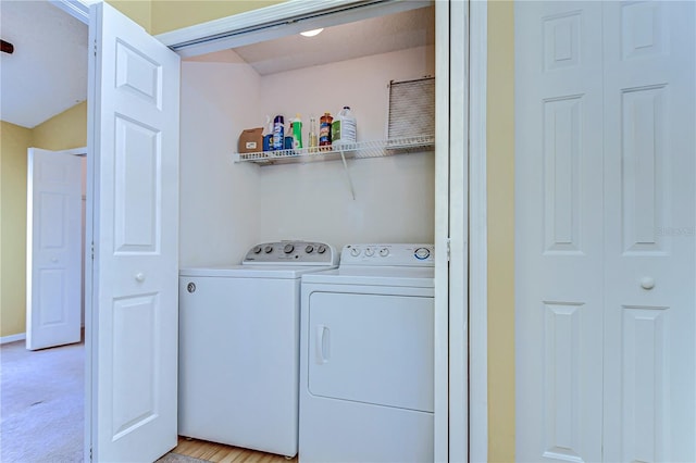 clothes washing area with light carpet, laundry area, and washer and clothes dryer