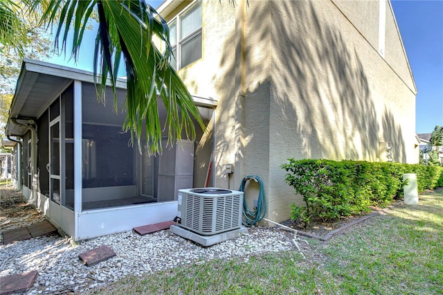 view of side of home featuring a sunroom, central AC, and stucco siding