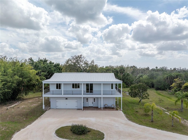 view of front of house featuring metal roof, driveway, a front lawn, and an attached garage