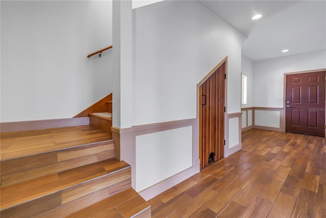 foyer entrance with stairs, wood finished floors, and recessed lighting