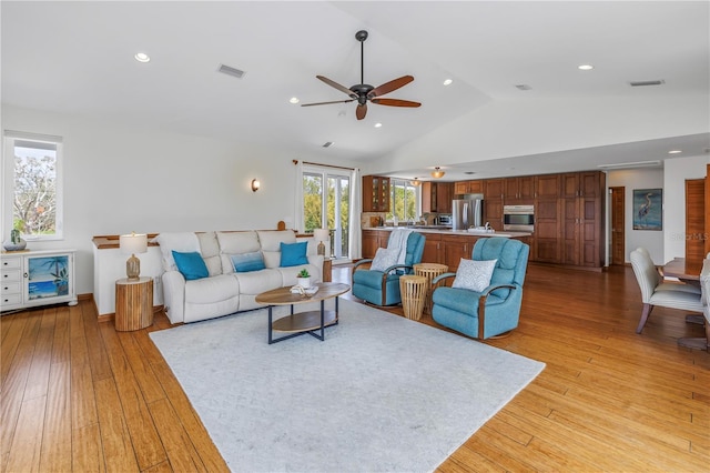 living room with vaulted ceiling, light wood finished floors, visible vents, and recessed lighting