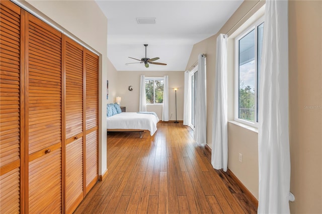 unfurnished bedroom with multiple windows, a closet, visible vents, and hardwood / wood-style flooring