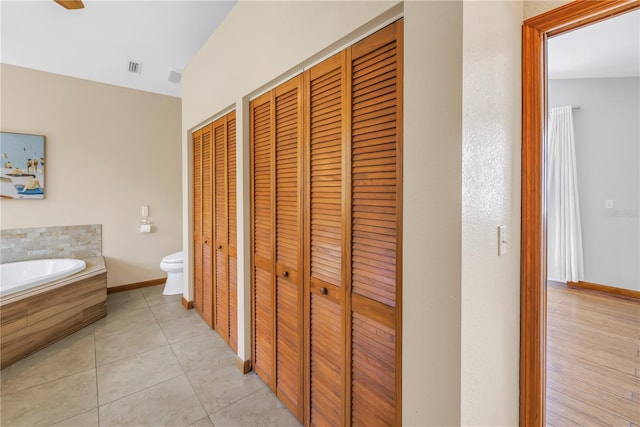 bathroom featuring a bath, toilet, a closet, and tile patterned floors