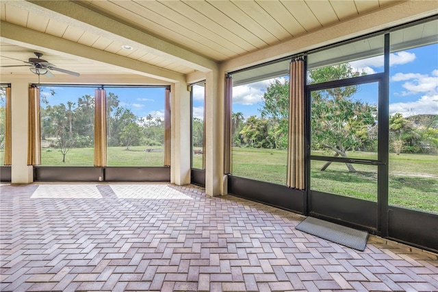 unfurnished sunroom featuring a healthy amount of sunlight, wooden ceiling, and a ceiling fan