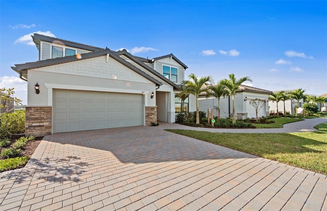 view of front of house featuring a garage, stone siding, a front lawn, and decorative driveway