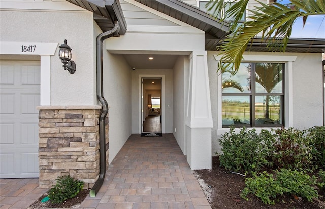 doorway to property with an attached garage and stucco siding