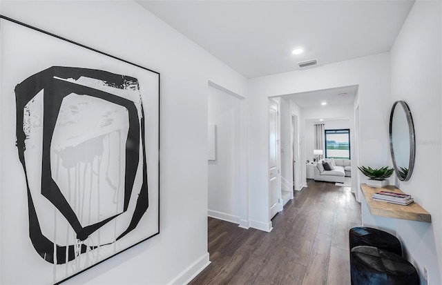 hallway featuring baseboards, visible vents, and wood finished floors