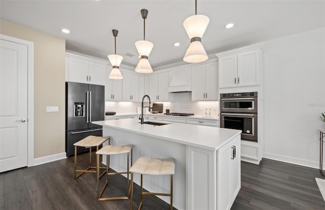 kitchen with custom exhaust hood, light countertops, multiple ovens, a sink, and high end refrigerator