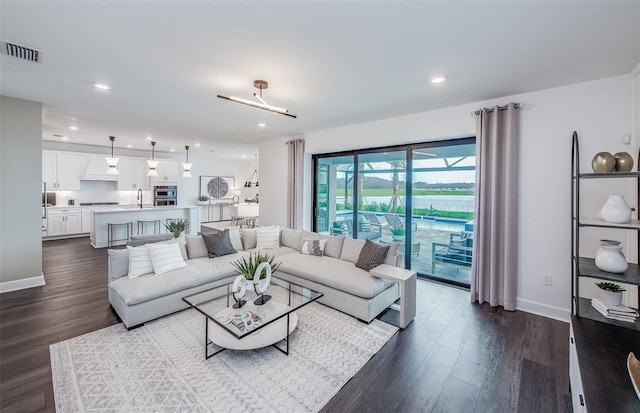 living area with visible vents, dark wood finished floors, and baseboards