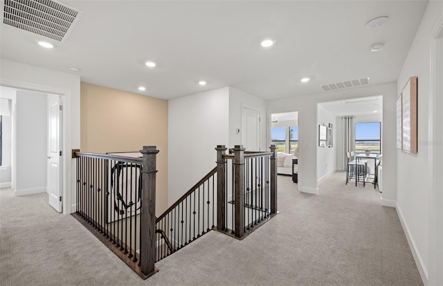 hallway featuring recessed lighting, visible vents, light colored carpet, and an upstairs landing