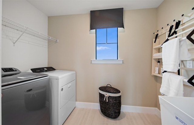 clothes washing area with baseboards, laundry area, light tile patterned floors, and washer and dryer