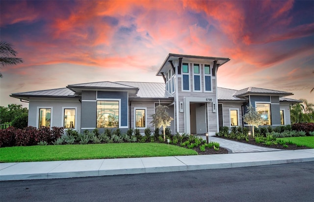 prairie-style house with a standing seam roof, decorative driveway, metal roof, and a lawn