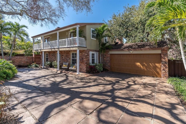 view of front of property featuring concrete driveway, a balcony, an attached garage, fence, and stucco siding